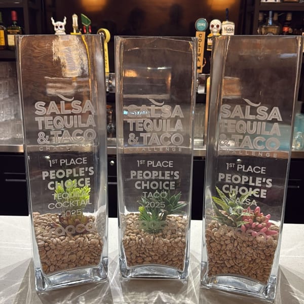 Three glass trophies from the Salsa Tequila & Taco Challenge, filled with beans and succulents.